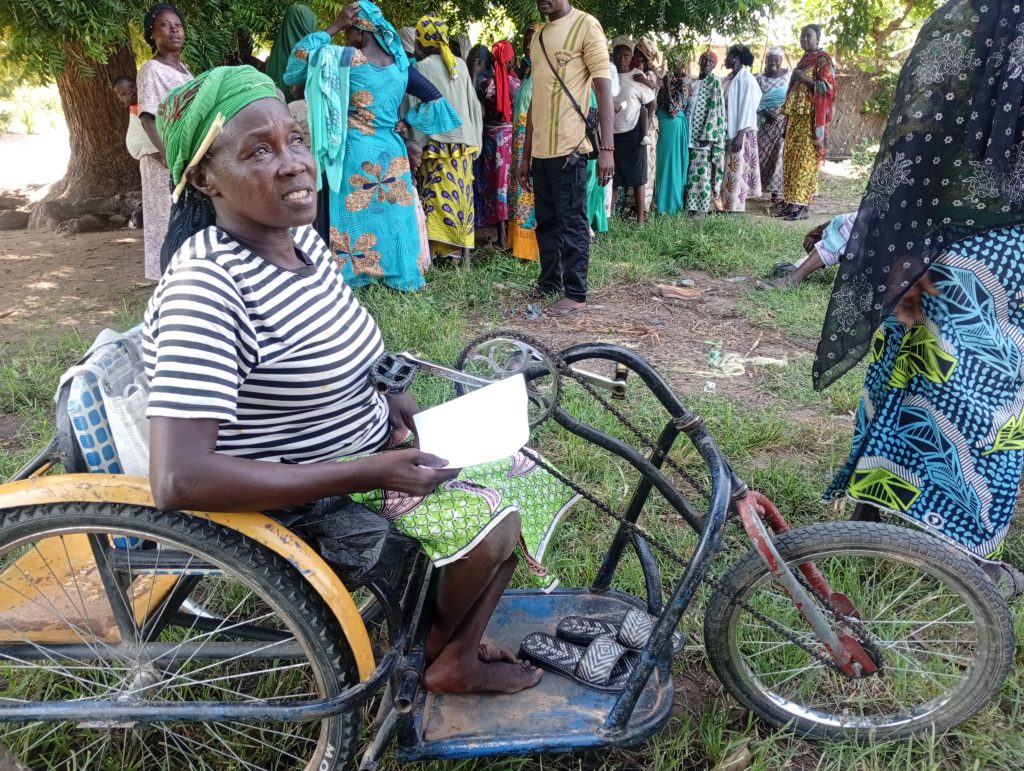 A beneficiary living with a disability waits in line alongside other participants to receive medical services during the outreach